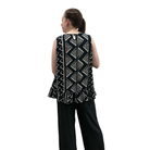 Woman wearing black with geometric print pattern sleeveless top with ruffle bottom on white background