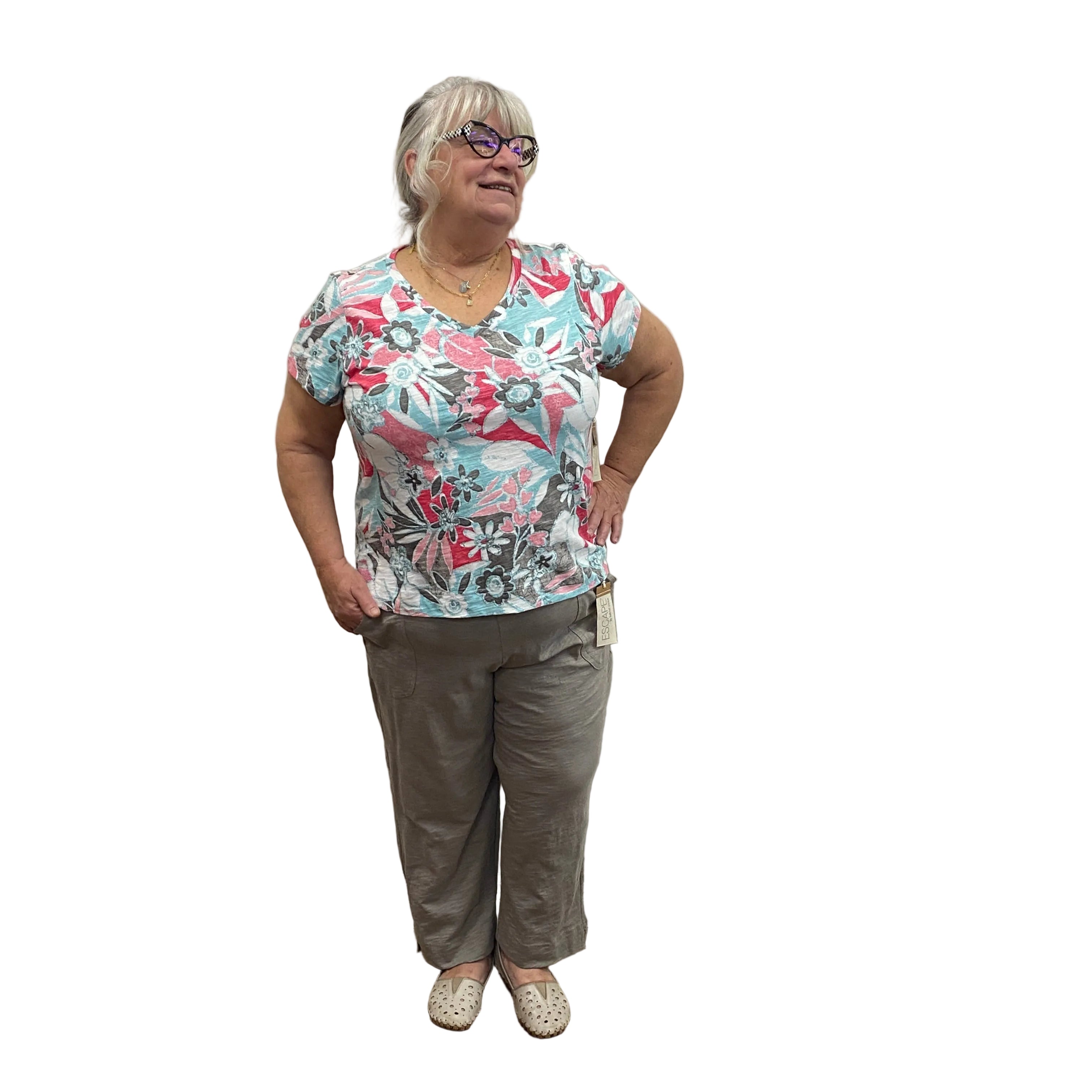 Person wearing a floral shirt and gray pants standing on white background. 