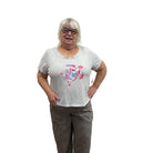 Person wearing a white Papa t-shirt with a pink turtle design and gray pants on white background. 