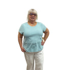 Person wearing a light blue striped Papa T-shirt and white pants on white background. 