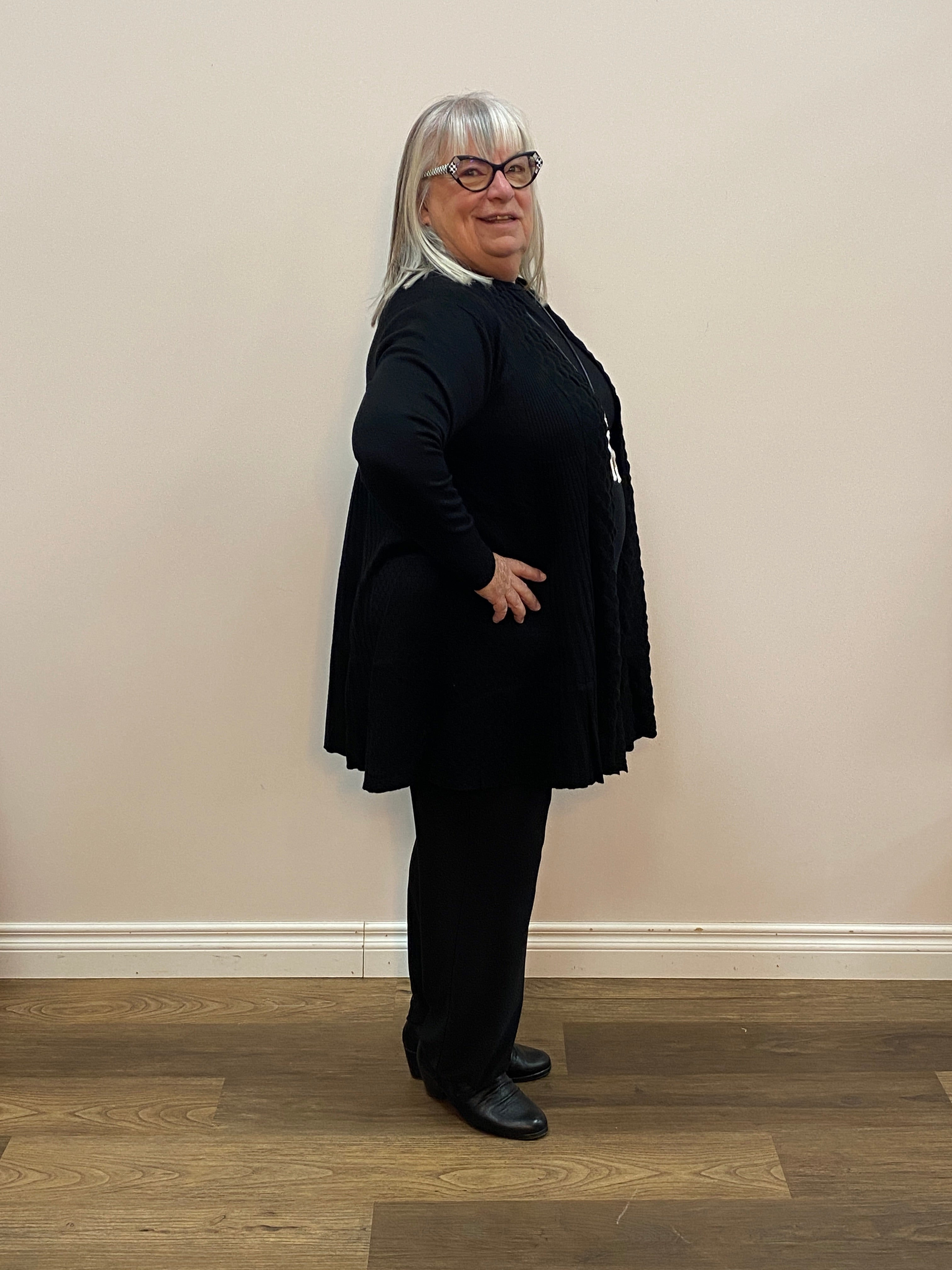 Person wearing a black cardigan in a minimal indoor setting