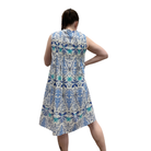 Woman wearing a sleeveless dress with a blue and green leaf pattern on a white background