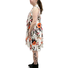 Woman wearing a sleeveless floral dress with orange flowers on a white background