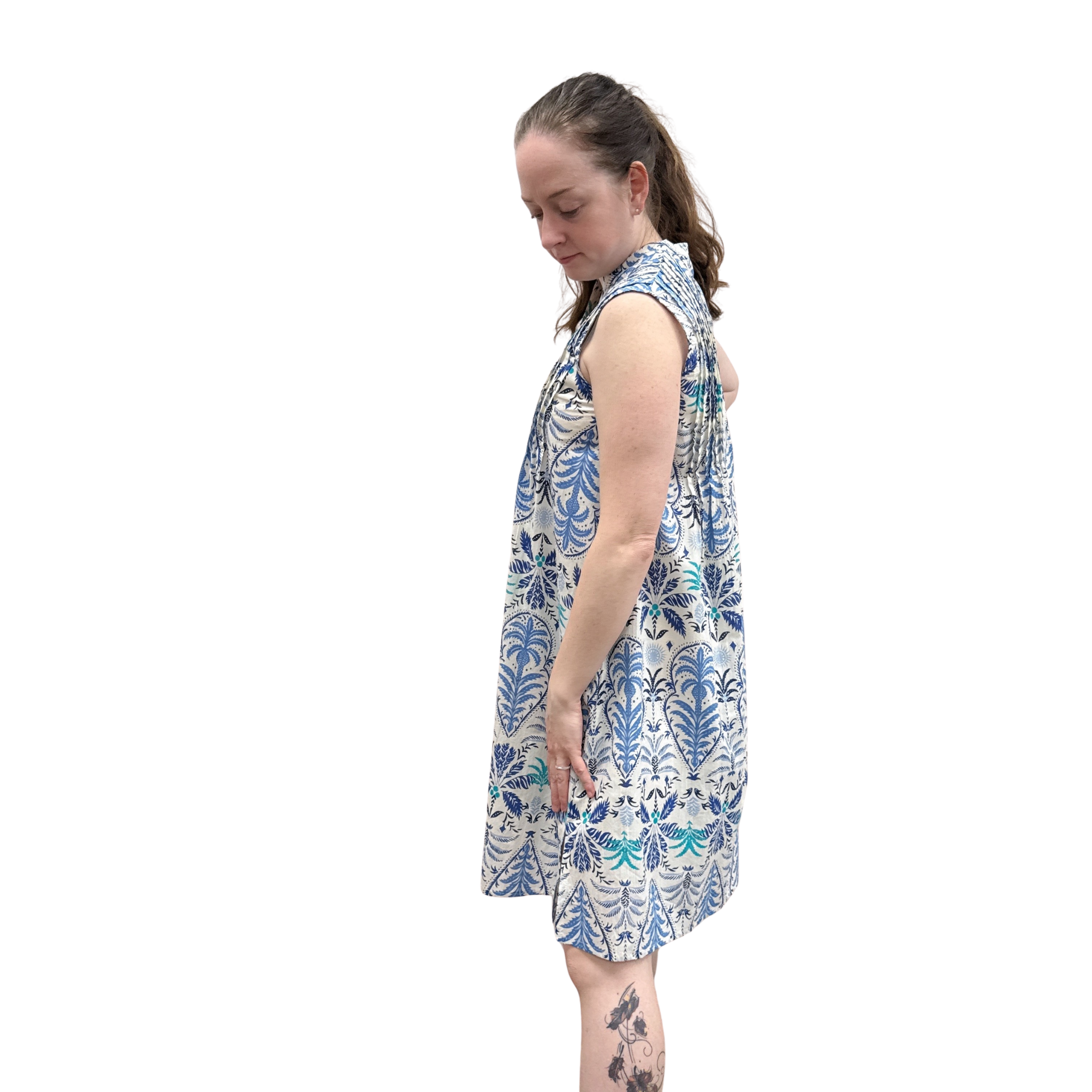 Woman wearing a sleeveless dress with a blue floral pattern on a white background