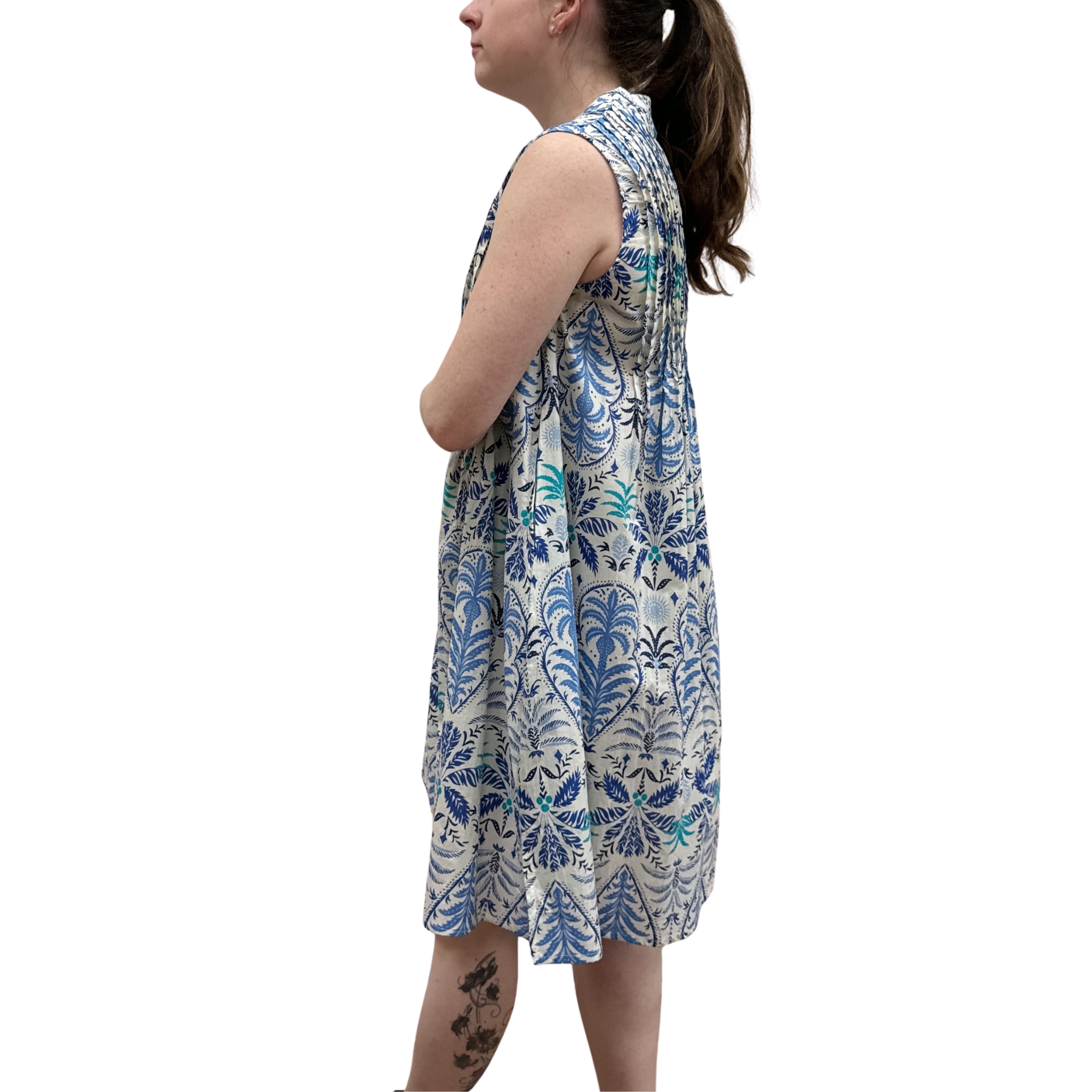 Woman wearing a sleeveless dress with blue floral pattern on a white background