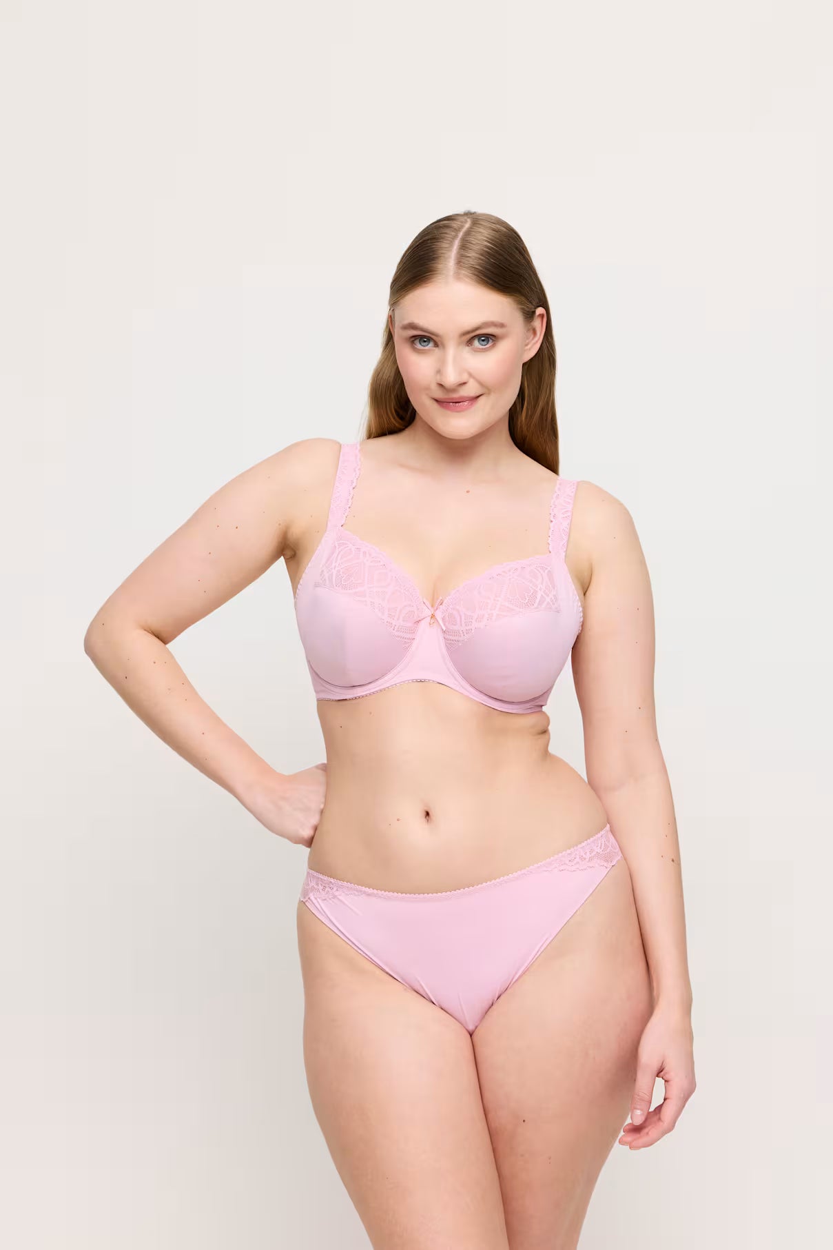 Woman wearing a pink bra and panties set on a light gray background
