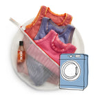 Soak Eco Wash bag shown with Soak detergent and clothing with a graphic of a washing machine to demonstrate that it can be used in the washing machine. 