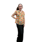 Woman wearing a colorful patterned shirt and black pants on a white background