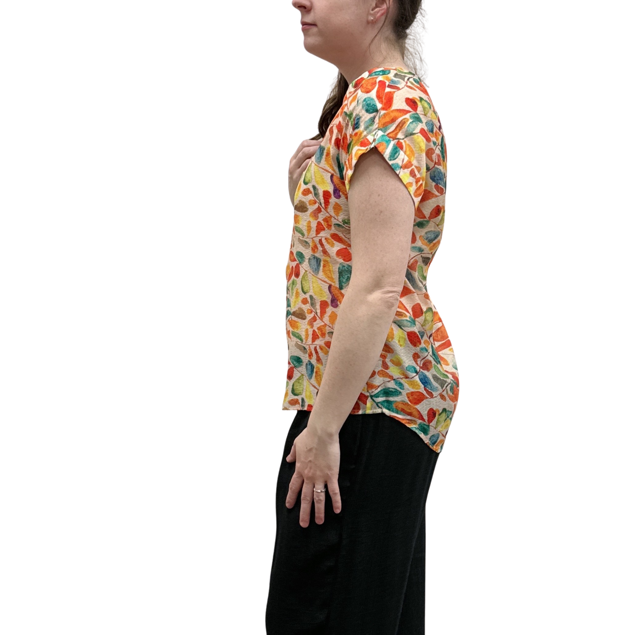 Woman wearing a colorful patterned shirt and black pants on a white background