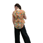 Person wearing a colorful patterned shirt and black pants on a white background