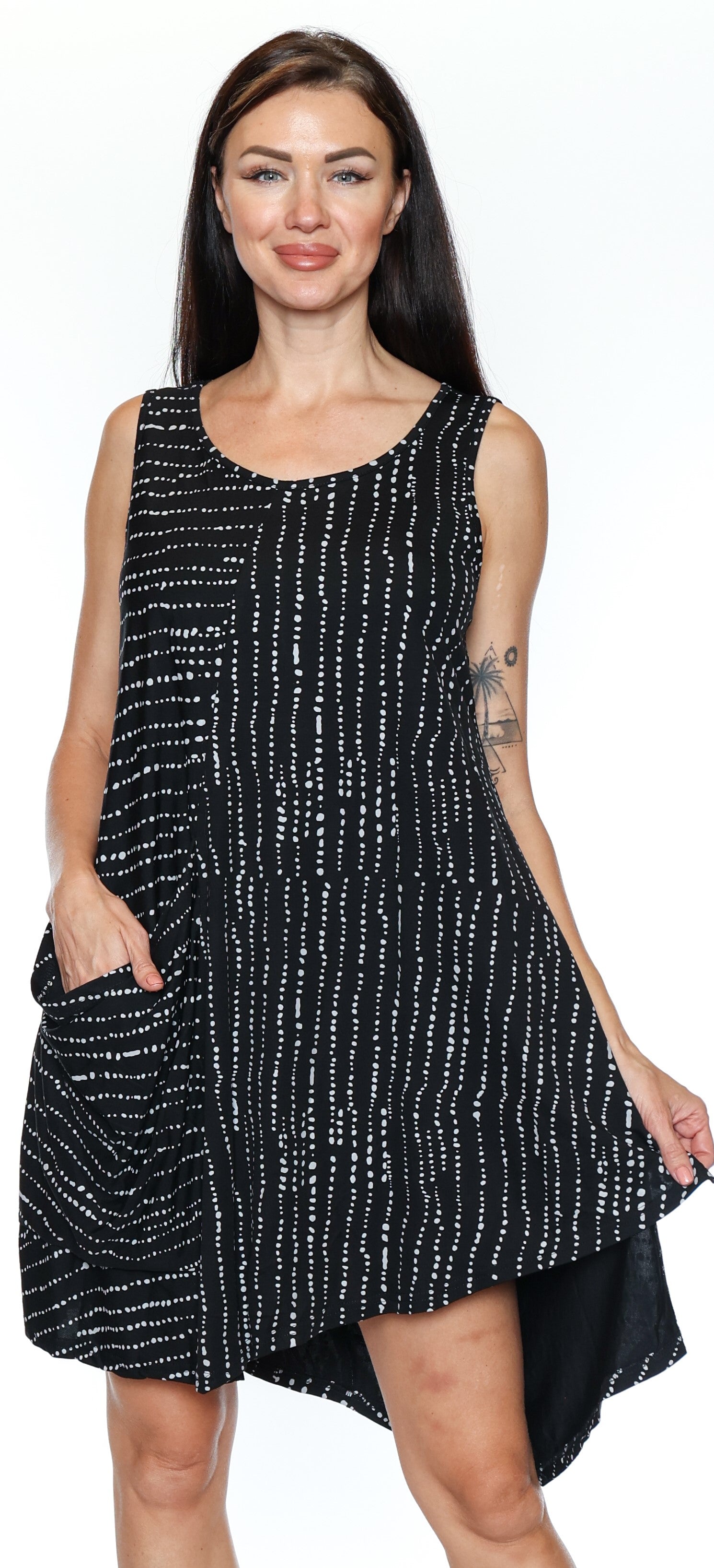 Woman wearing a black sleeveless dress with white patterns on a white background