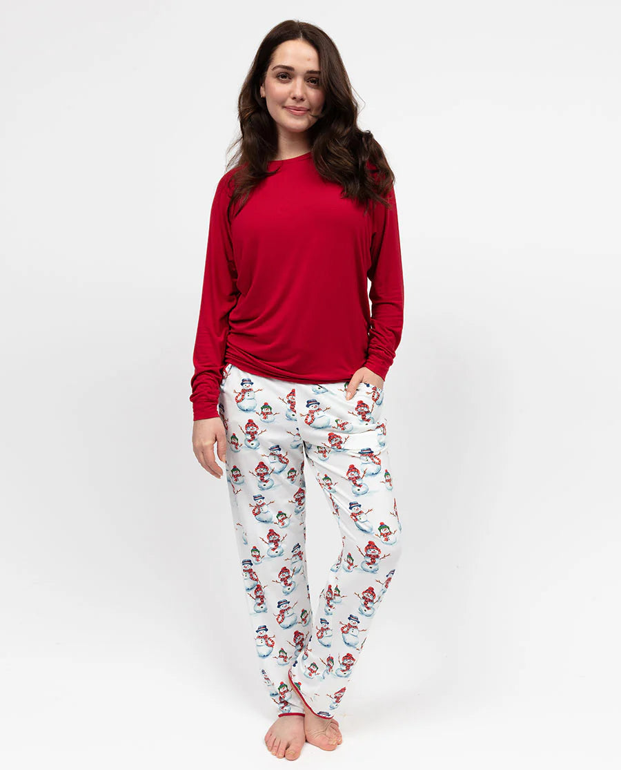 Woman wearing a red top and white pajama pants with snowman pattern on a white background