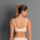 Woman wearing a beige bra against a gray background