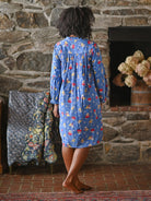 A person wearing a blue nighty against a grey wall