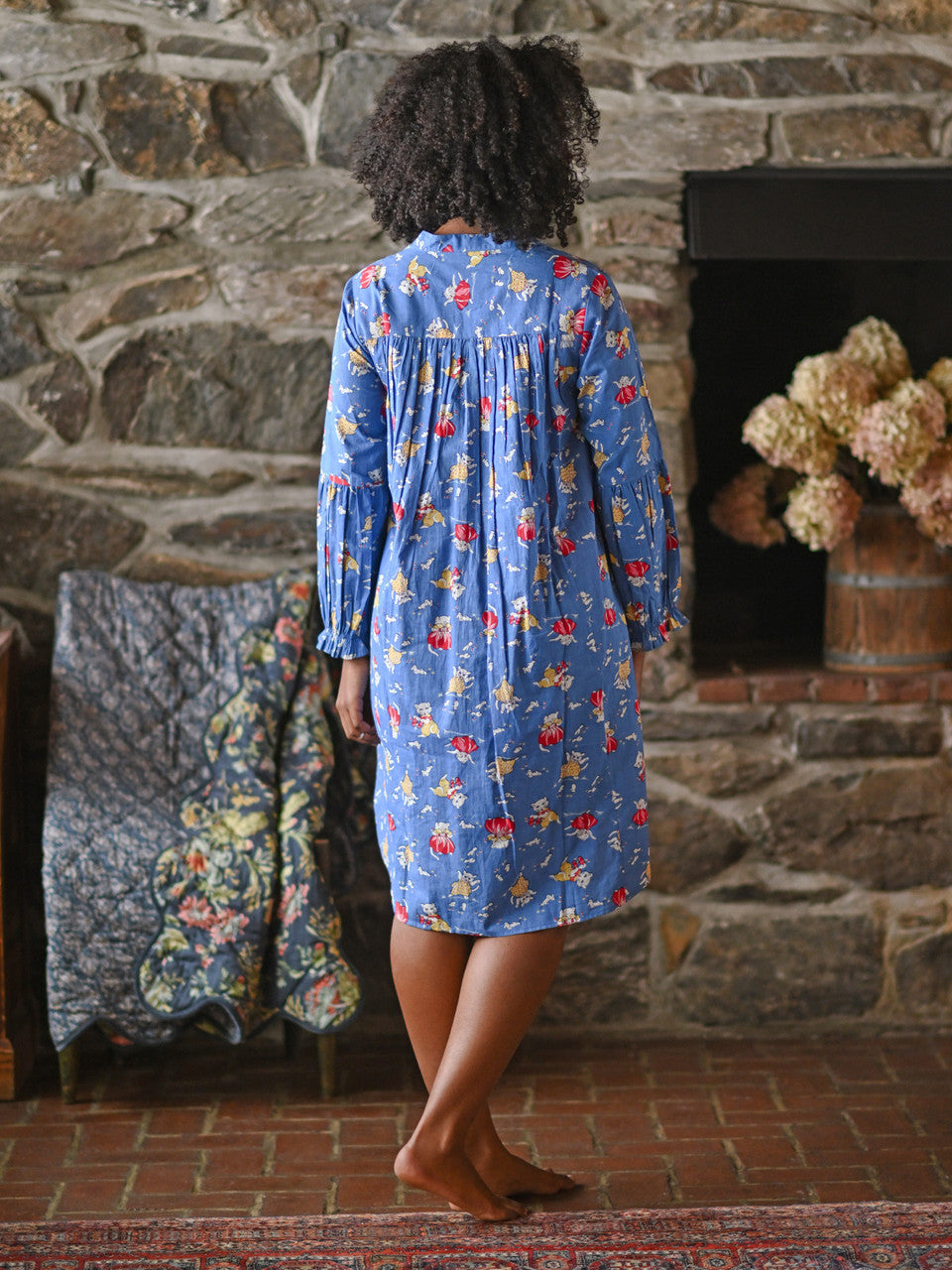 A person wearing a blue nighty against a grey wall