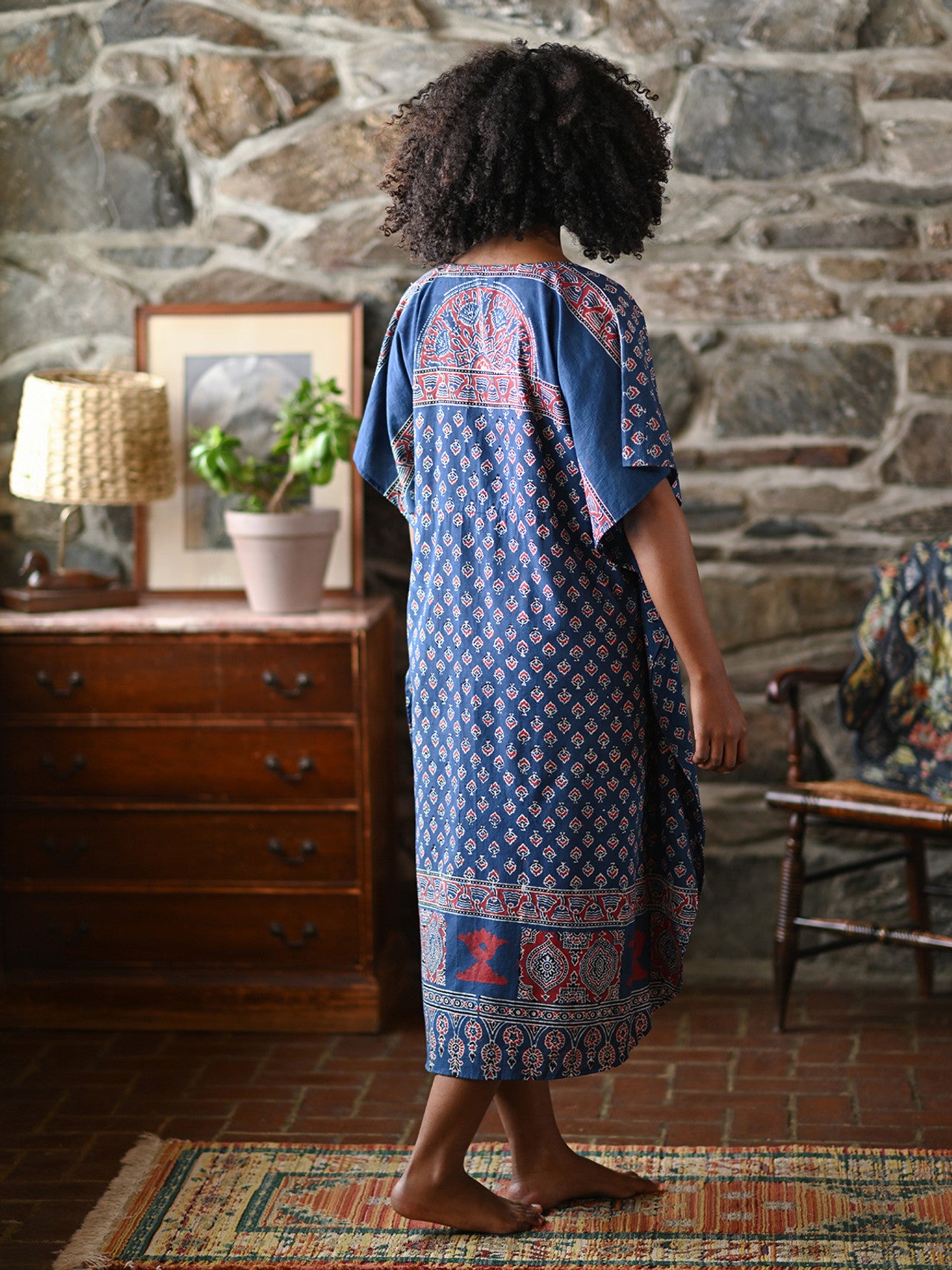 A person wearing a blue check dress in a living room