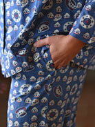 A persona wearing a blue and white shirt and pants with pockets. 