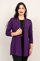 Woman wearing a purple cardigan over a black top on a white background
