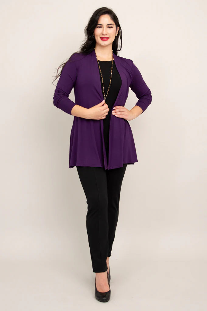 Woman wearing a purple blazer over a black top and pants on a beige background