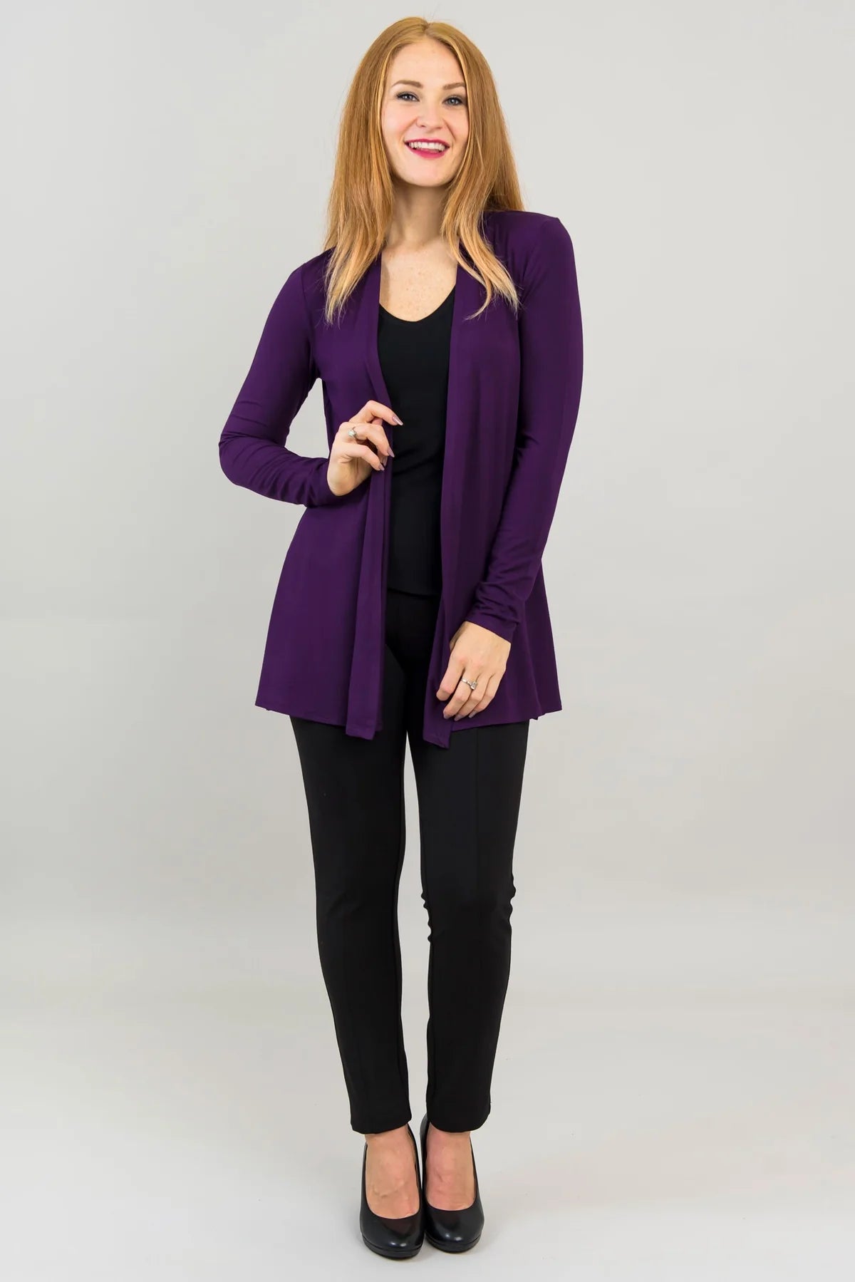 Woman wearing a purple blazer over a black top and pants on a white background
