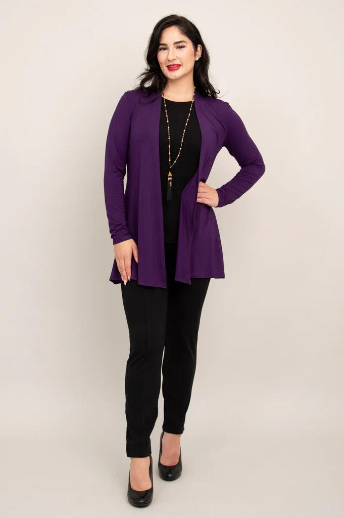 Woman wearing a purple cardigan over a black top and pants on a beige background