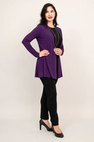 Woman wearing a purple cardigan over a black top and pants on a white background