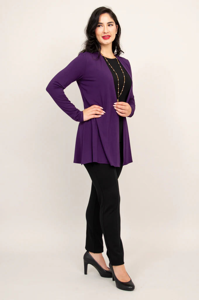 Woman wearing a purple cardigan over a black top and pants on a white background