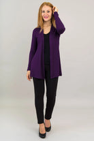 Woman wearing a purple cardigan over a black top and pants on a white background