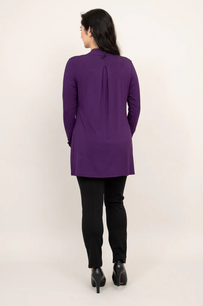 Person wearing a purple tunic and black pants on a white background