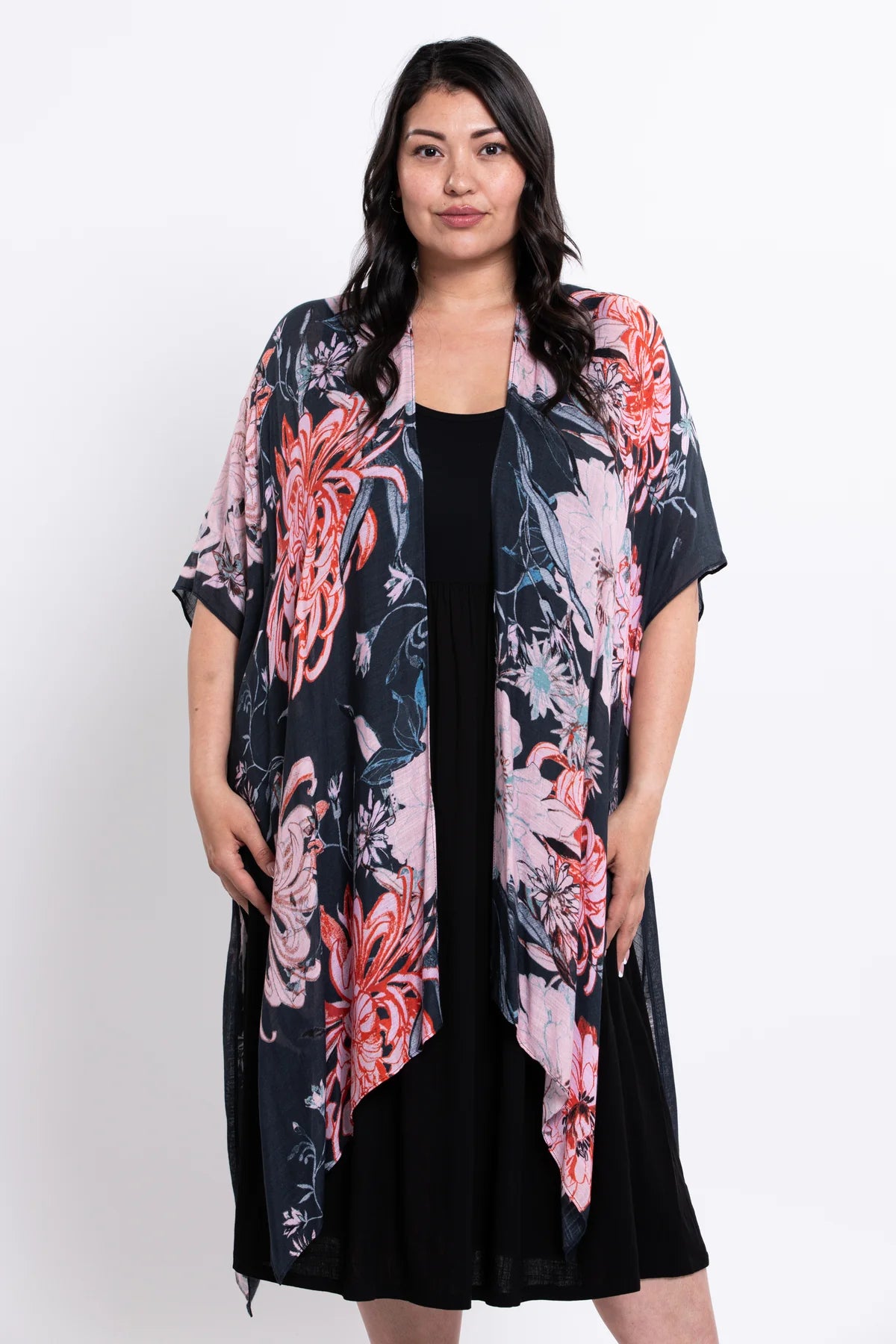 Woman wearing a floral kimono over a black dress on a white background