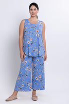 Woman wearing a blue floral sleeveless top and wide-leg pants on a white background