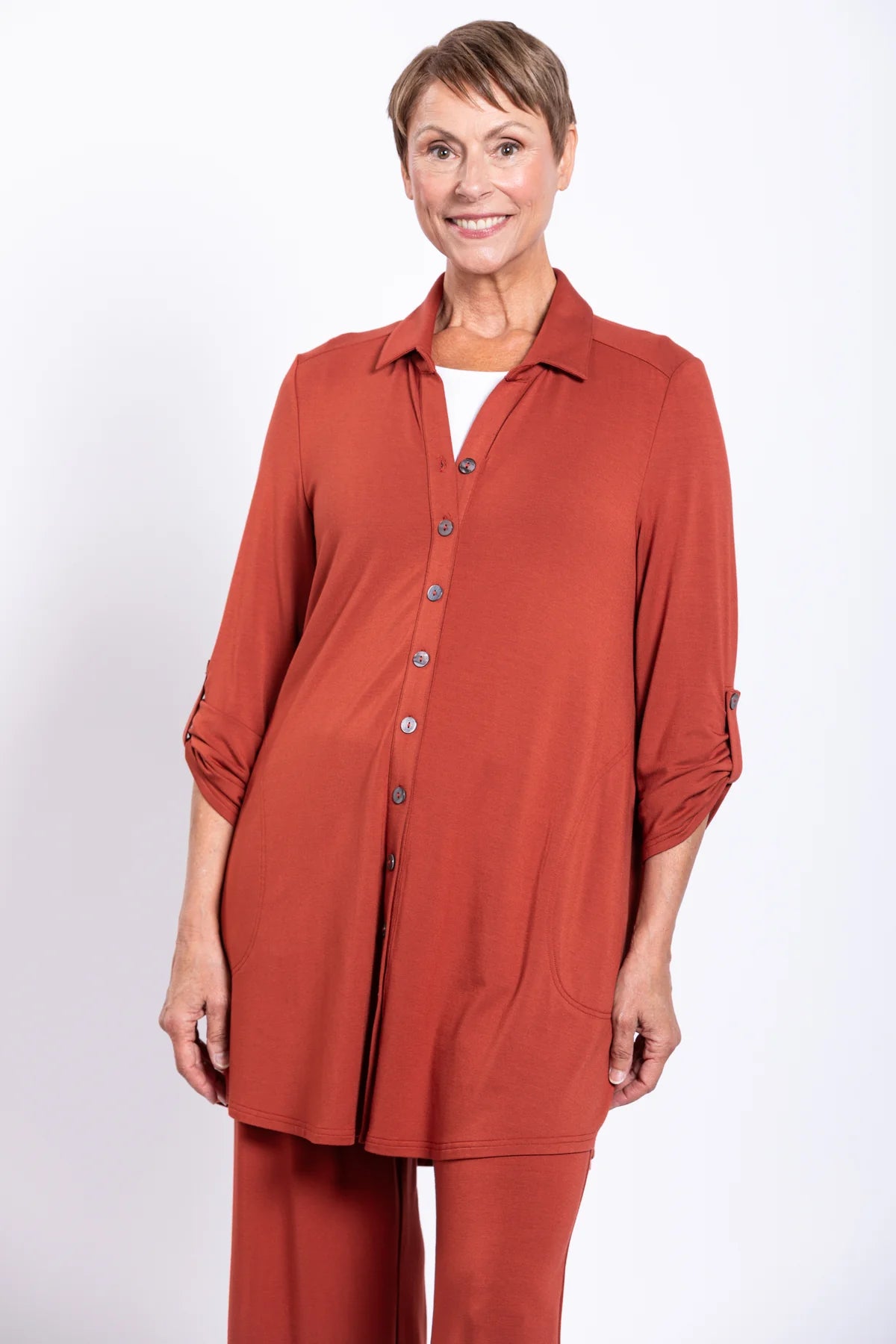 Woman wearing a rust-colored shirt and pants on a white background