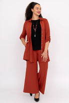 Woman wearing a rust-colored outfit with a black top on a white background