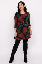 Woman wearing a patterned dress with black leggings and boots on a white background