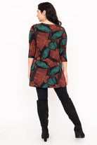 Woman wearing a patterned dress with long sleeves and black boots on a white background
