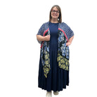 Woman wearing a navy dress with a floral Blue Sky Darcy kimono on a white background. 
