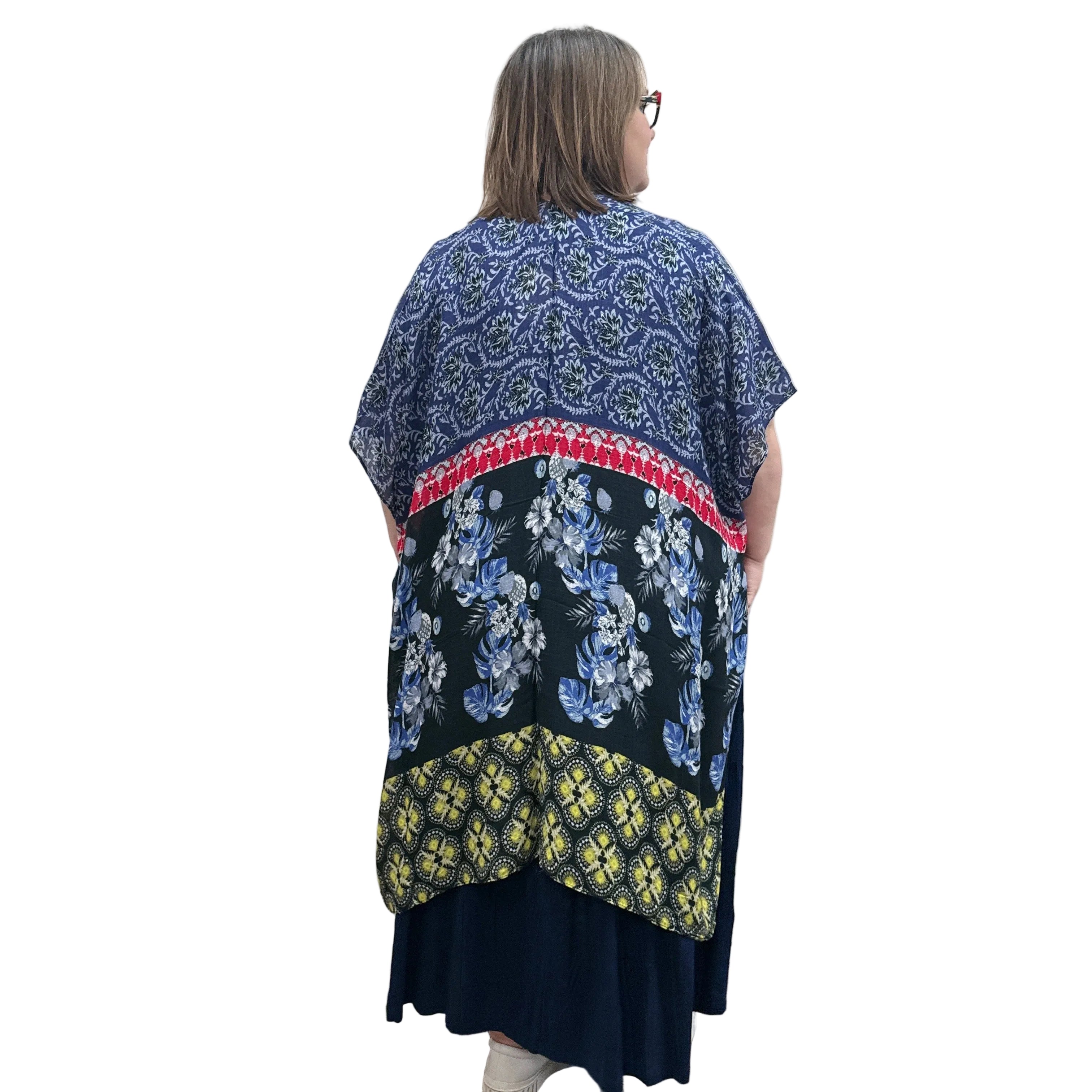 Woman wearing a navy dress with a floral Blue Sky Darcy kimono on a white background. 