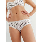 The Micro Hipster Panty in dots; white panty with black polka dots shown on a model wearing a matching bralette. 