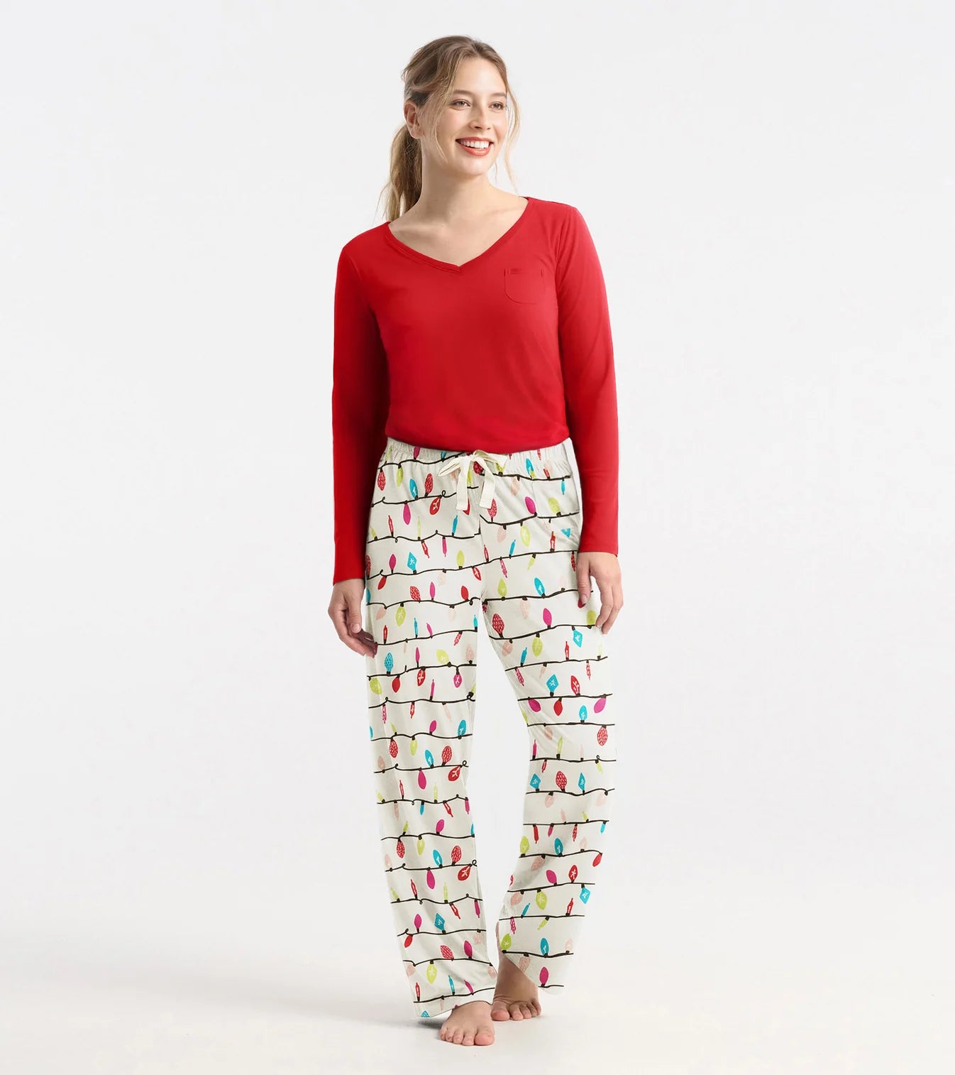 Woman wearing a red top and patterned pajama pants on a white background