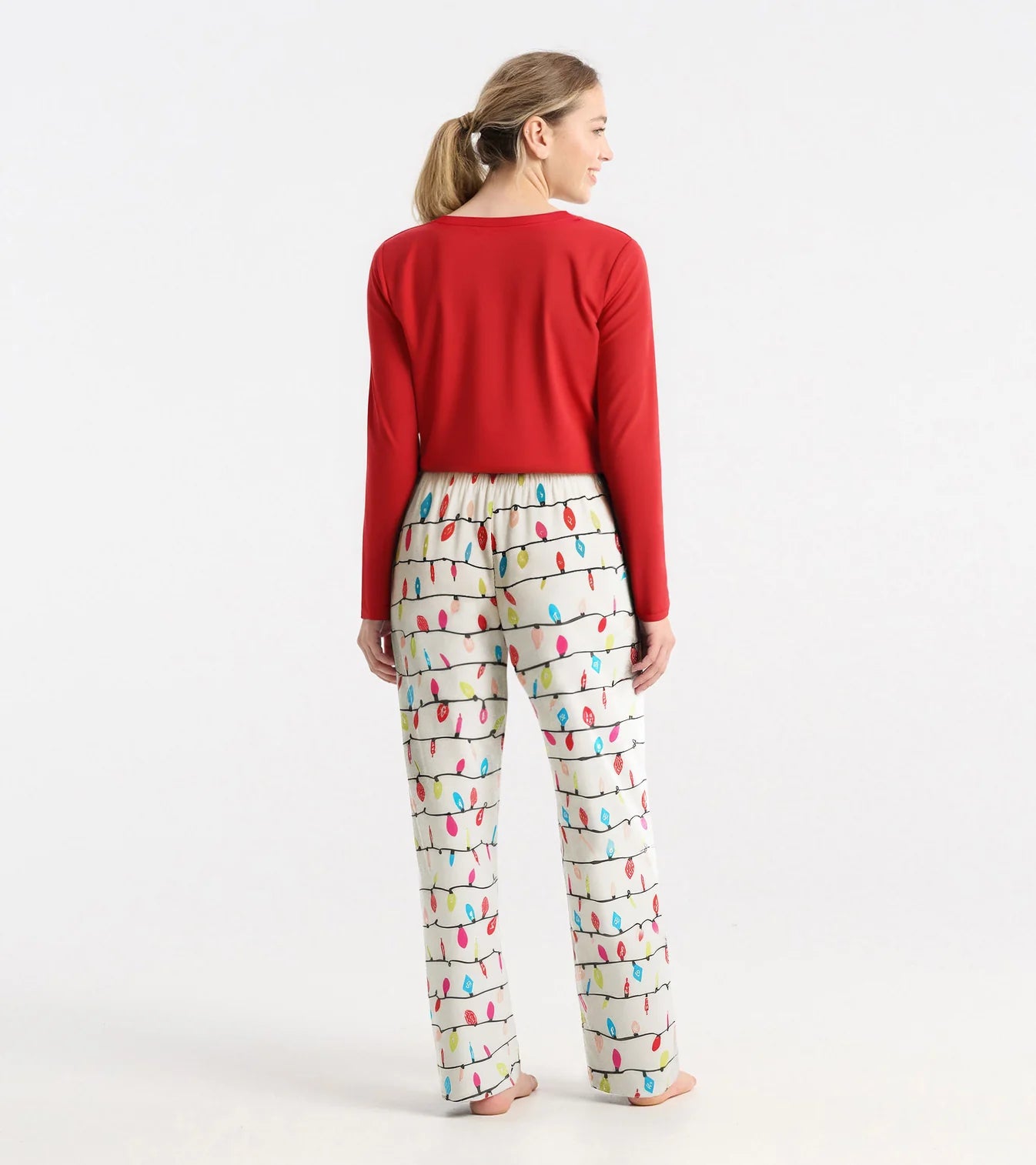 Woman wearing a red top and colorful patterned pants on a white background