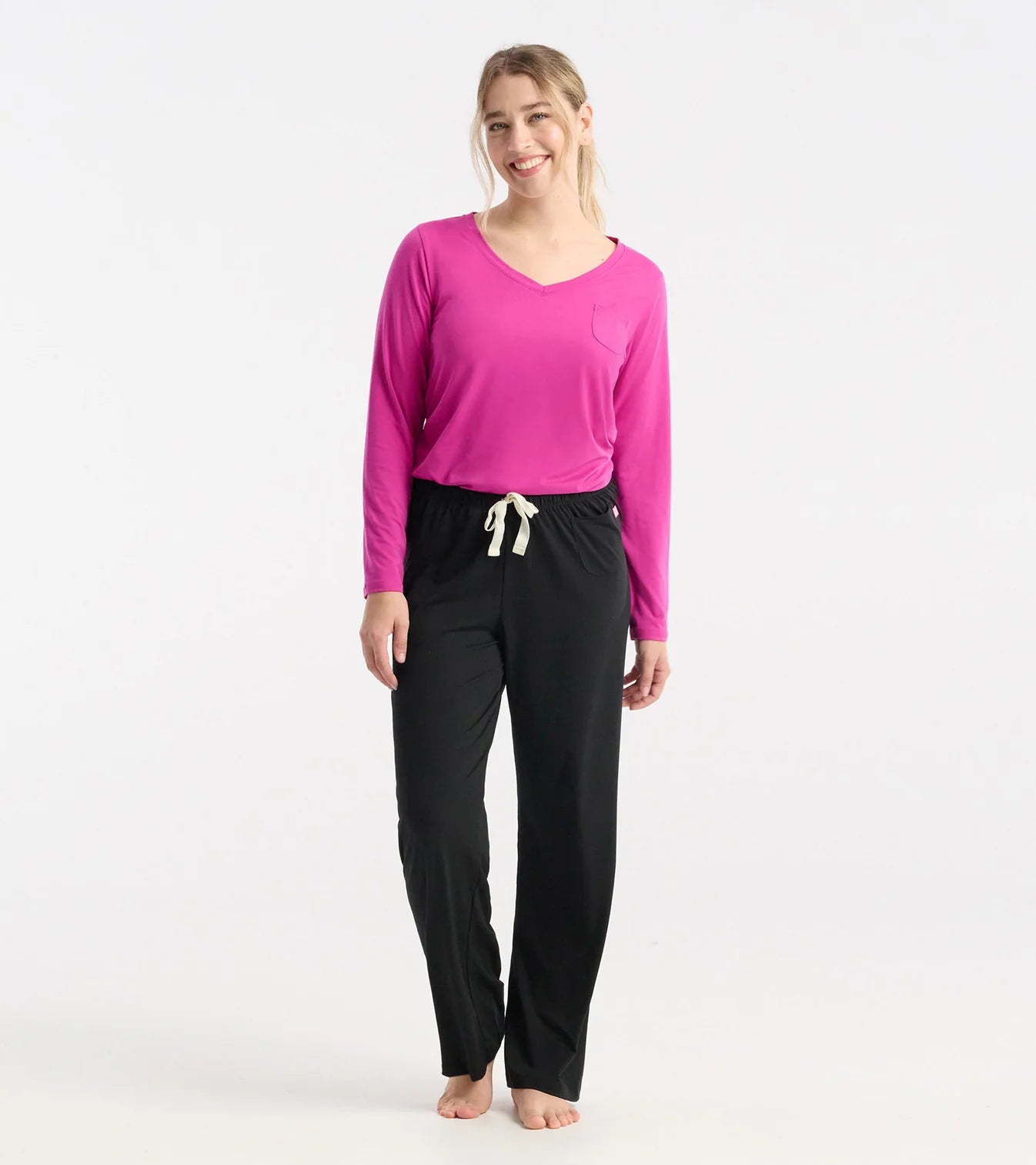Woman wearing a pink long-sleeve top and black pants on a white background