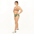 Woman wearing a brown bralette and green underwear set on a white background