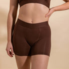 Brown boxer briefs worn by a person on a beige background
