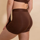 Brown athletic shorts worn by a person on a beige background