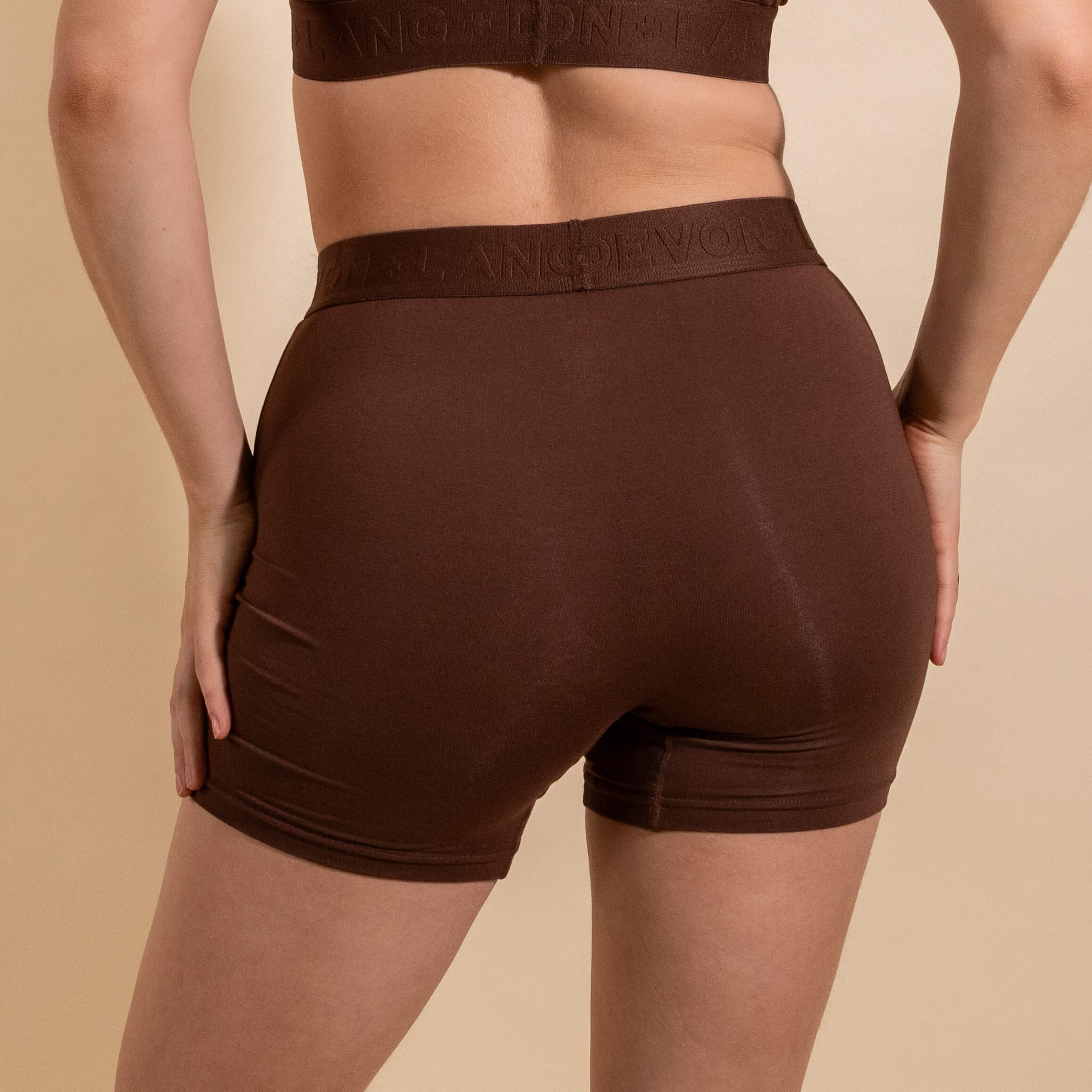 Brown athletic shorts worn by a person on a beige background