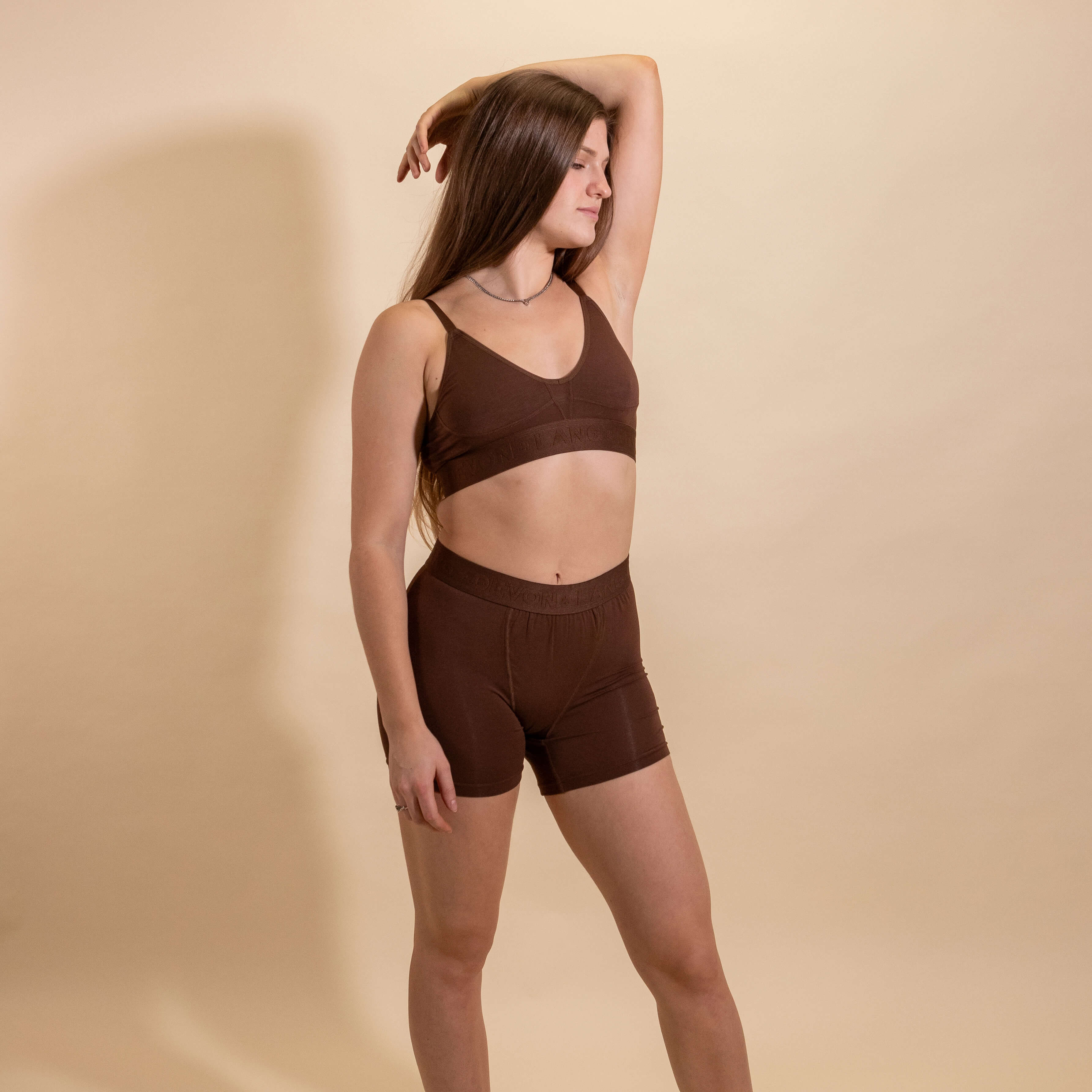 Woman wearing a brown bralette and shorts set against a beige background