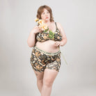 Woman wearing a floral lingerie set holding flowers against a plain background