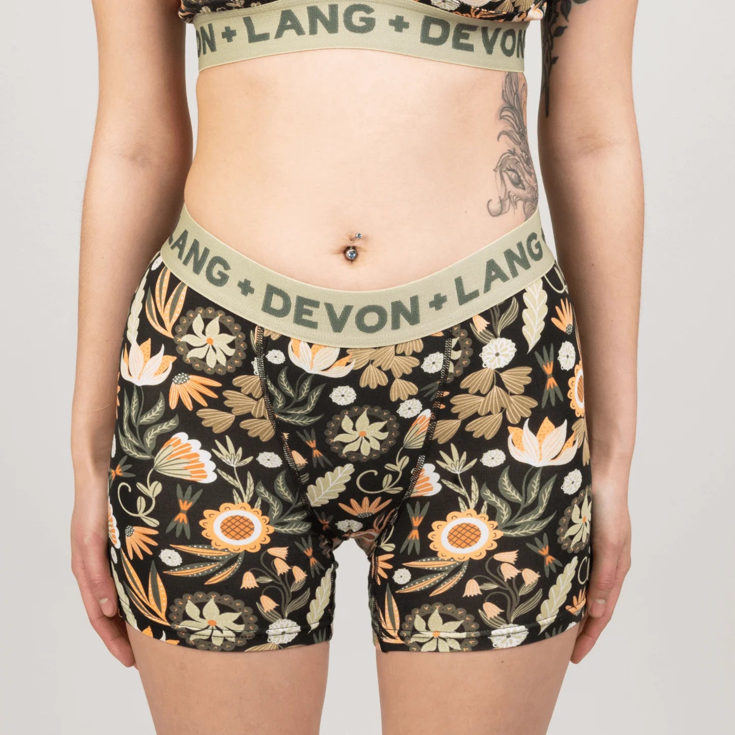 Person wearing floral-patterned underwear with 'Devon + Lang' branding on a plain background
