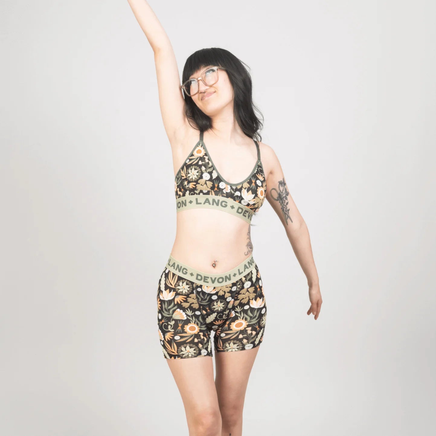 Woman wearing a patterned bralette and shorts set with ''Devon + Lang'' branding on a plain background