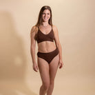 Woman wearing a brown underwear set on a beige background